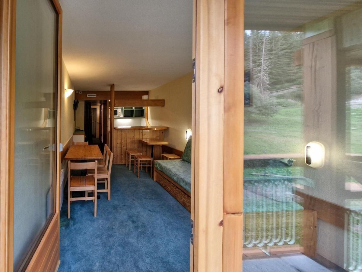Une pièce de taille modeste comprenant une table à manger, des chaises, un canapé et une petite kitchenette.