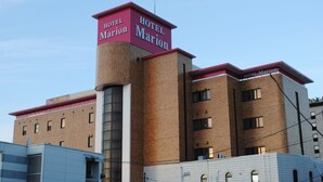 A hotel named 'Hotel Marion' with a distinctive red and brown facade, multiple windows, and a visible sign indicating 'GRAND OPEN'. - Hotel Marion (Suzuka)