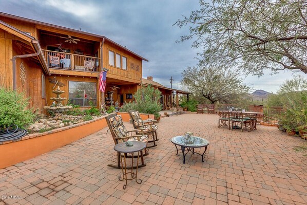 A wooden building with a patio area featuring outdoor furniture and a fountain. - Spur Cross Inn (Cave Creek)