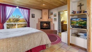 Ein Schlafzimmer mit Bett, Kamin, Fernseher und Bücherregal.