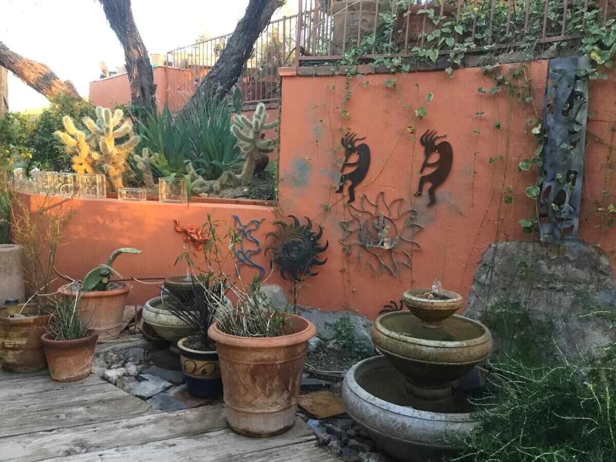 Een binnentuin met potplanten, een decoratieve muur met dierenbeeldhouwwerken en een fontein met meerdere lagen.