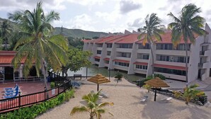 A resort with a pool, palm trees, and a building with a red roof. - Waterfront Condominium Complex with Beautiful Sea Views 3 Bedroom 3 Bath  (Christiansted)