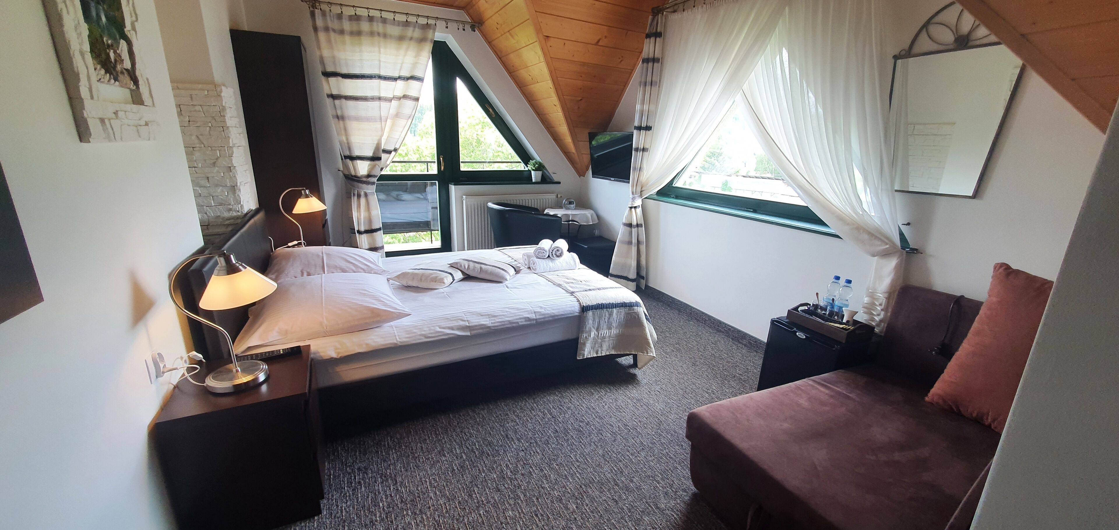 A bedroom with a bed, a desk with a lamp, a chair, a window with curtains, and a radiator.