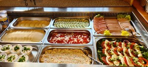 A buffet with various food options including sliced cucumbers, tomatoes, and a salad. - Gościniec Na Brzyzku (Bukowina Tatrzanska)