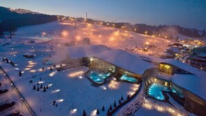 Ein schneebedecktes Resort mit Außen-Whirlpools und einer Skipiste.
