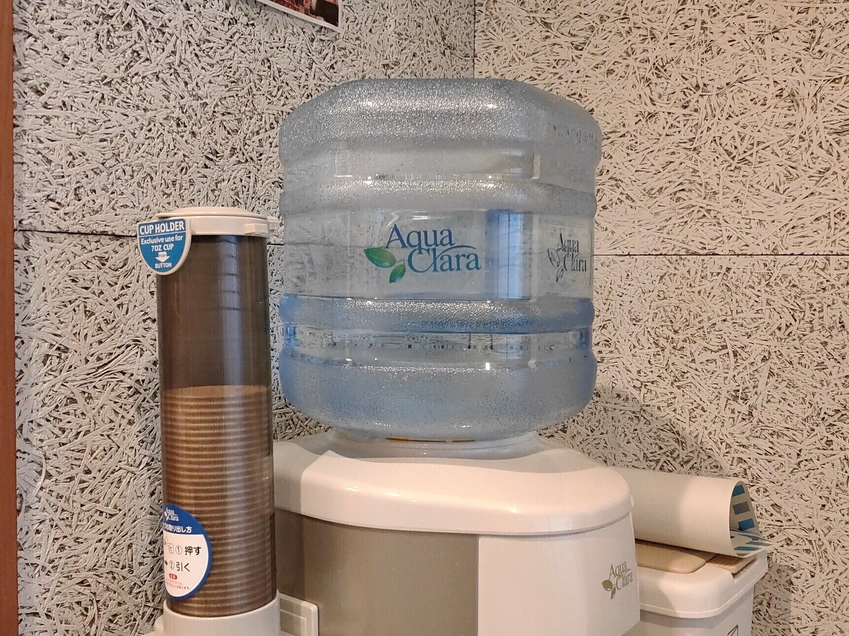 Un dispensador de agua con un botellón y un portavasos.