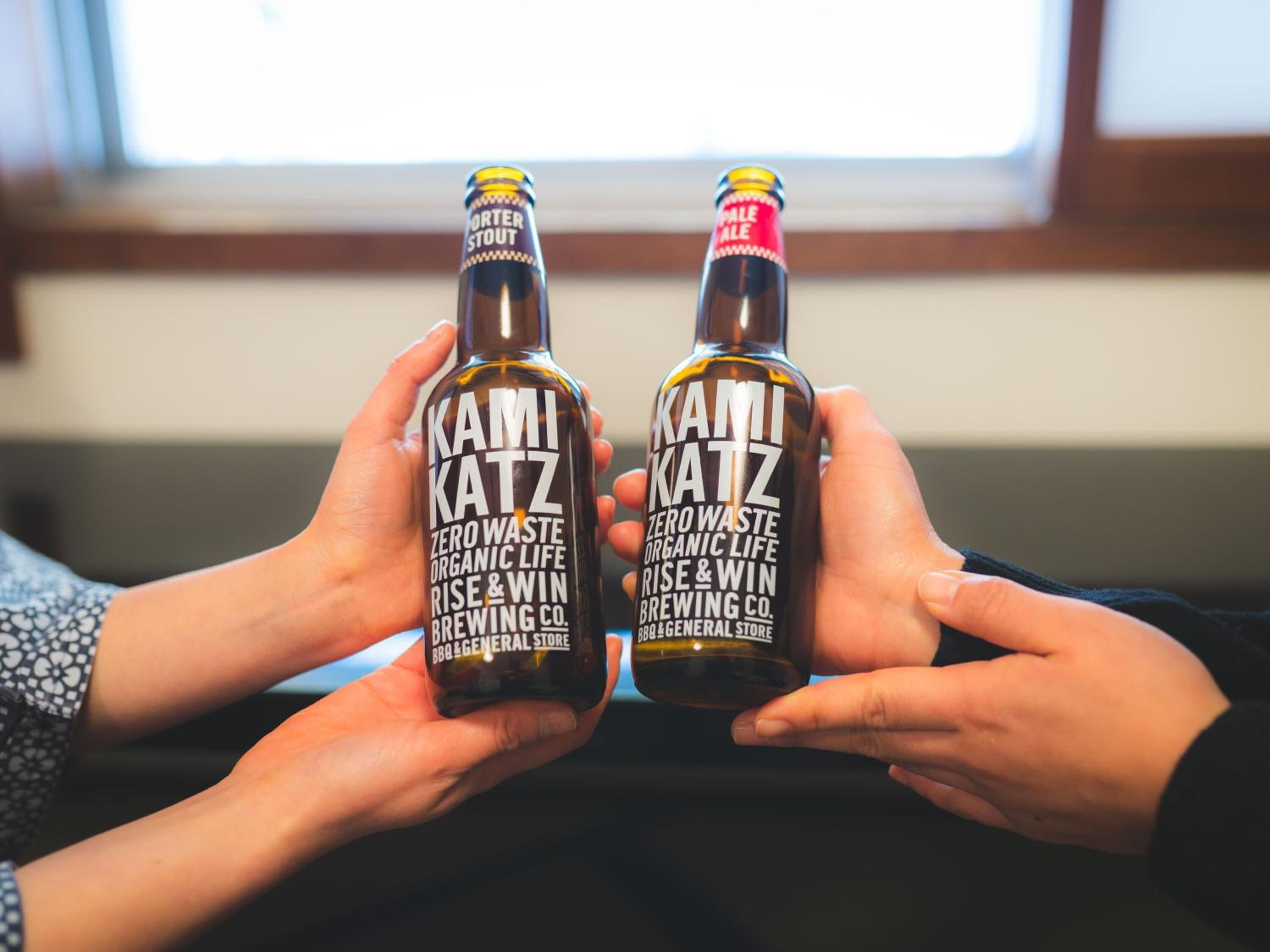 Deux bouteilles de bière Kamikatz tenues dans des mains.