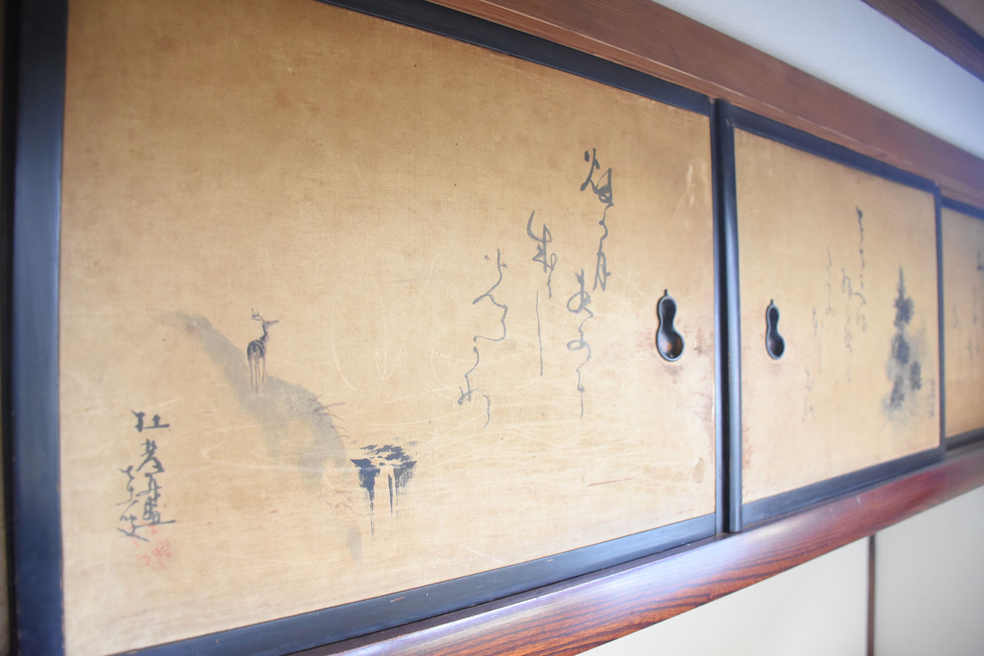 A traditional Japanese sliding door with calligraphy and a deer illustration.