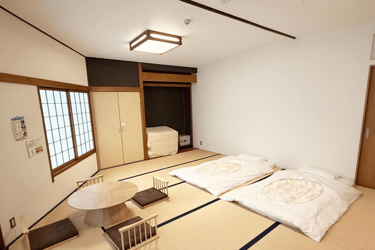 A traditional Japanese room with tatami flooring, a low table, and a futon bed.