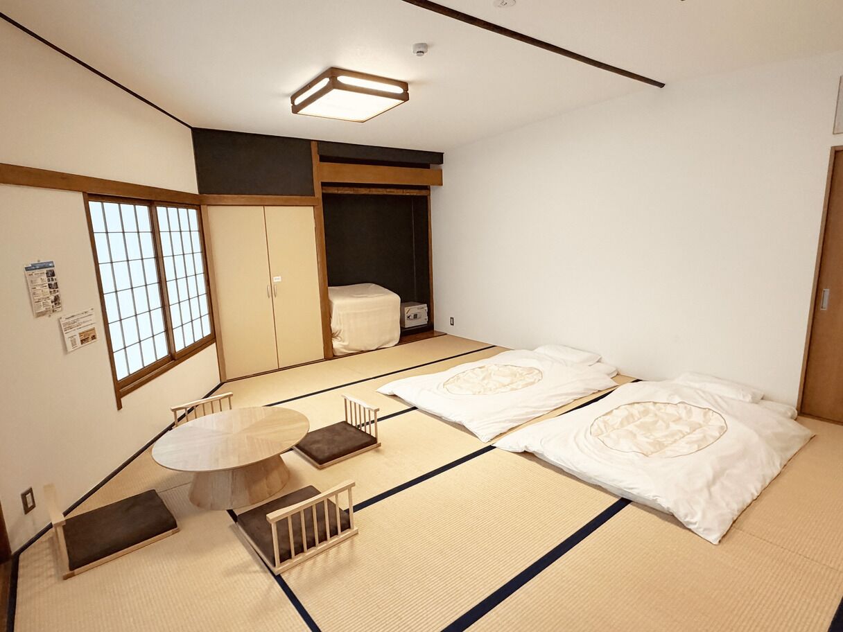 A traditional Japanese room with tatami flooring, a low table, and a futon bed.