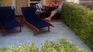 Een balkon met twee loungestoelen, een tafel en een stoel.
