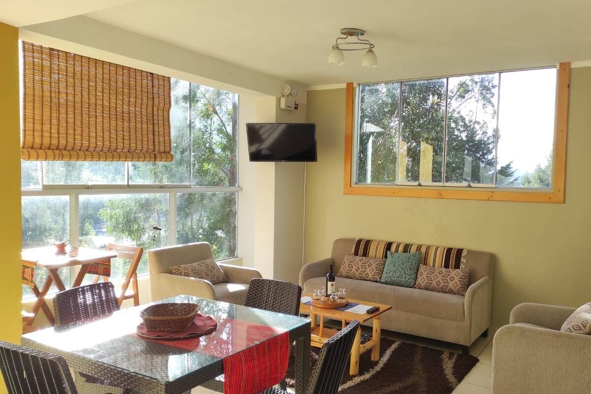 A living room with a sofa, chairs, a table, and a TV.