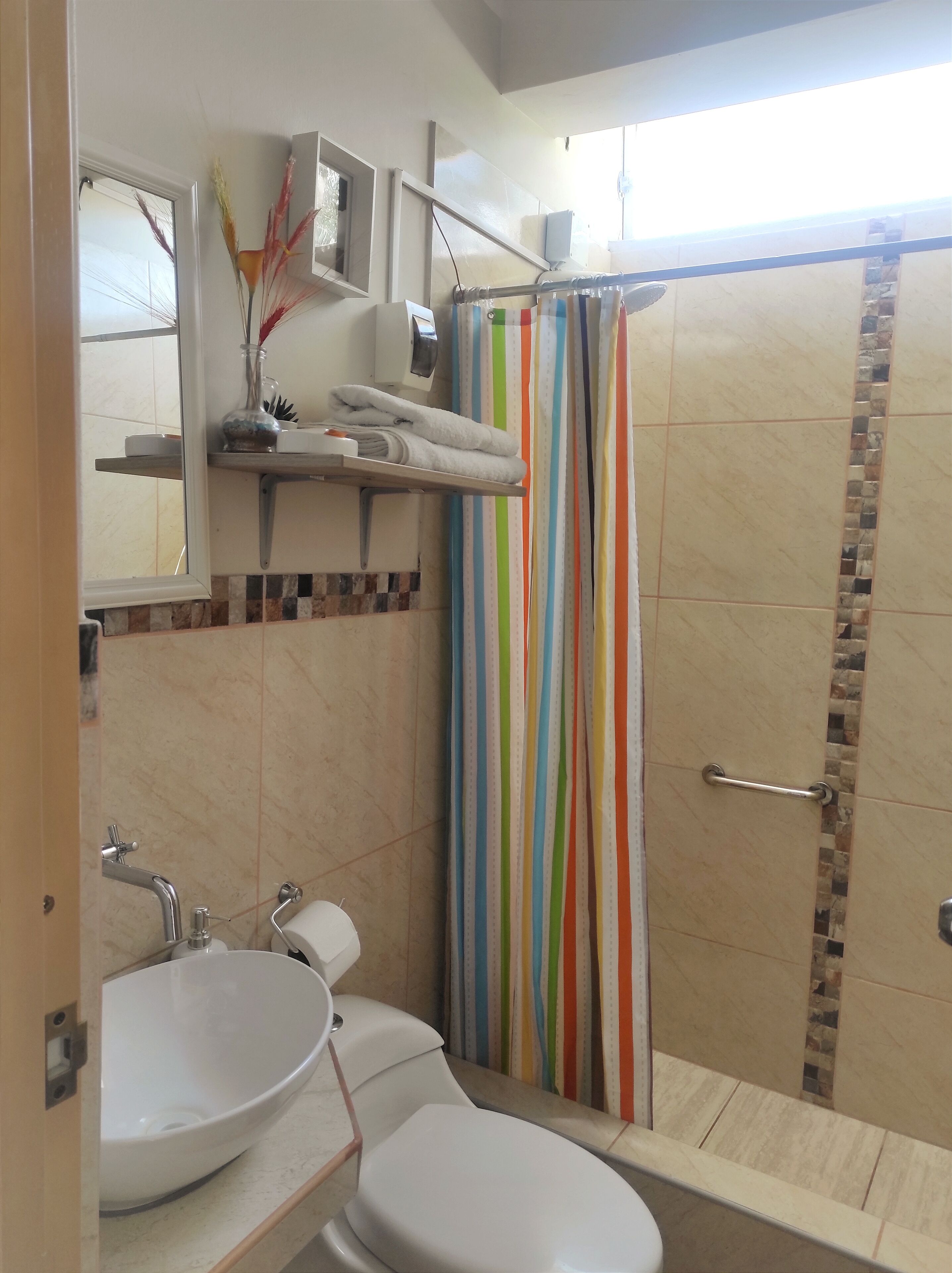 Un bagno con lavandino, wc e tenda da doccia a righe.