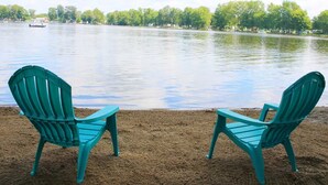 Two turquoise Adirondack chairs facing a lake with a boat in the distance and trees lining the shore. - The Sanctuary on Golden Lake (Pleasant Lake)