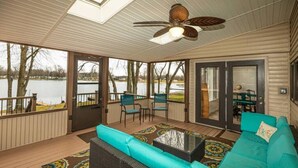 A covered outdoor deck with a sofa, chairs, and a table. - The Sanctuary on Golden Lake (Pleasant Lake)