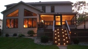 A two-story house with a covered front porch and a staircase leading to the entrance. - The Sanctuary on Golden Lake (Pleasant Lake)