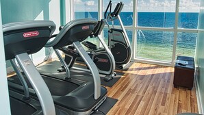 Una palestra con tapis roulant e attrezzature per esercizi, ampie finestre vista mare.