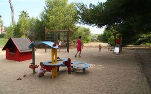 Children can play on the climbing frame and slide in this outdoor play area surrounded by trees.