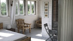 Ein Zimmer mit einem Bett, zwei Holzstühlen, einem Tisch und einem Fenster mit Jalousien.