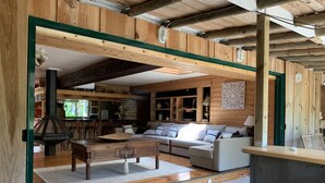 Ein gemütliches Holzinterieur mit einer Couch, einem Esstisch und einem Kamin aus Stein.