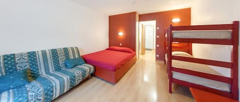 A room with a bunk bed, a sofa, and a bed.