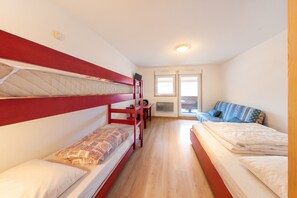 A dormitory room with bunk beds, a single bed, a desk, and a window. - Homerez - Studio in Gérardmer (Gérardmer)