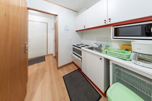 A compact kitchen with a microwave, stove, and sink.