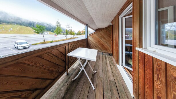 A wooden interior with a table and a window overlooking a road. - Homerez - Studio in Gérardmer (Gérardmer)