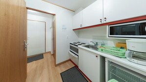 A compact kitchen with a microwave, stove, and sink. - Homerez - Studio in Gérardmer (Gérardmer)