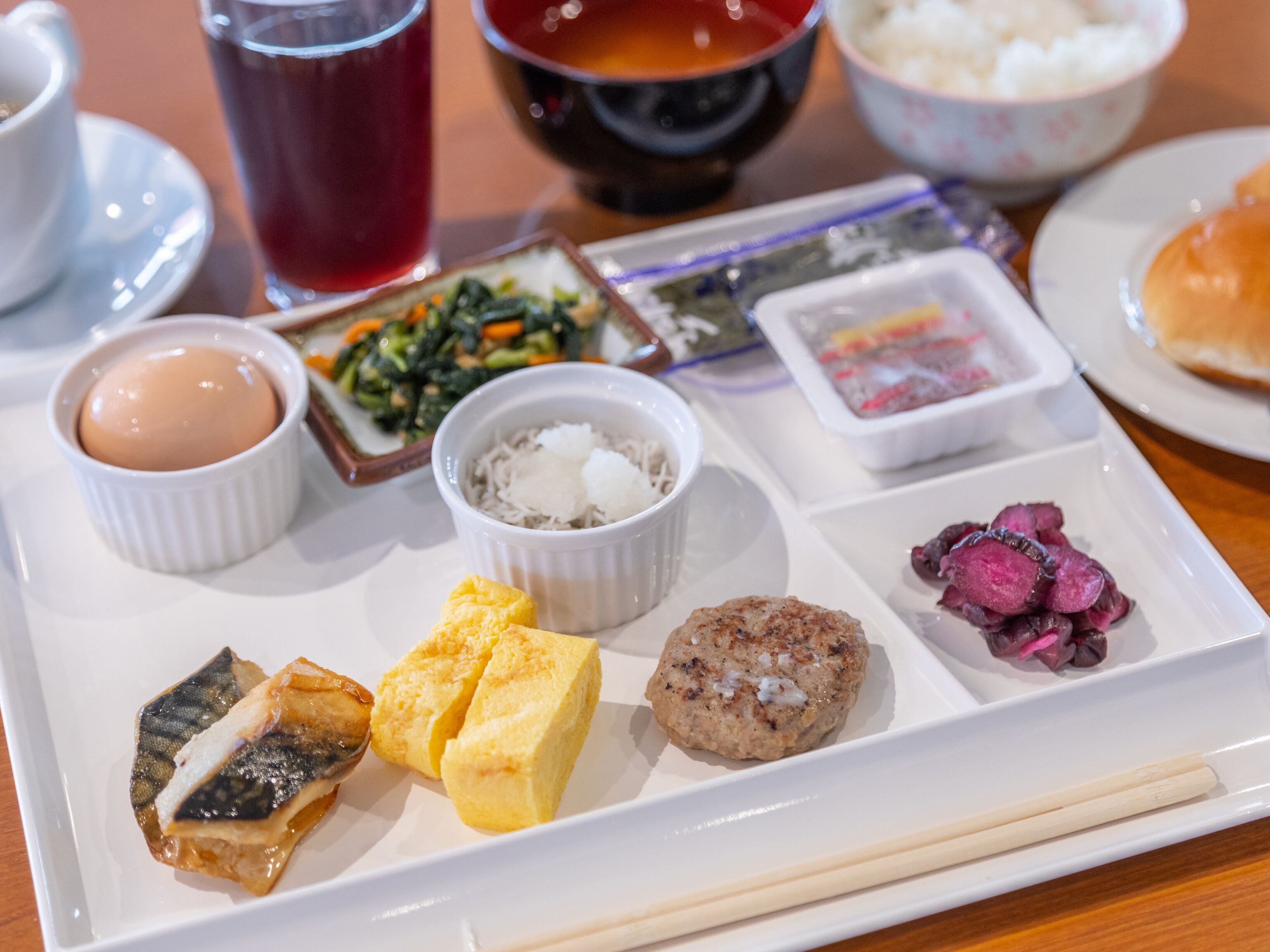 A traditional Japanese meal with various dishes including sushi, tempura, and pickled vegetables on a white tray.