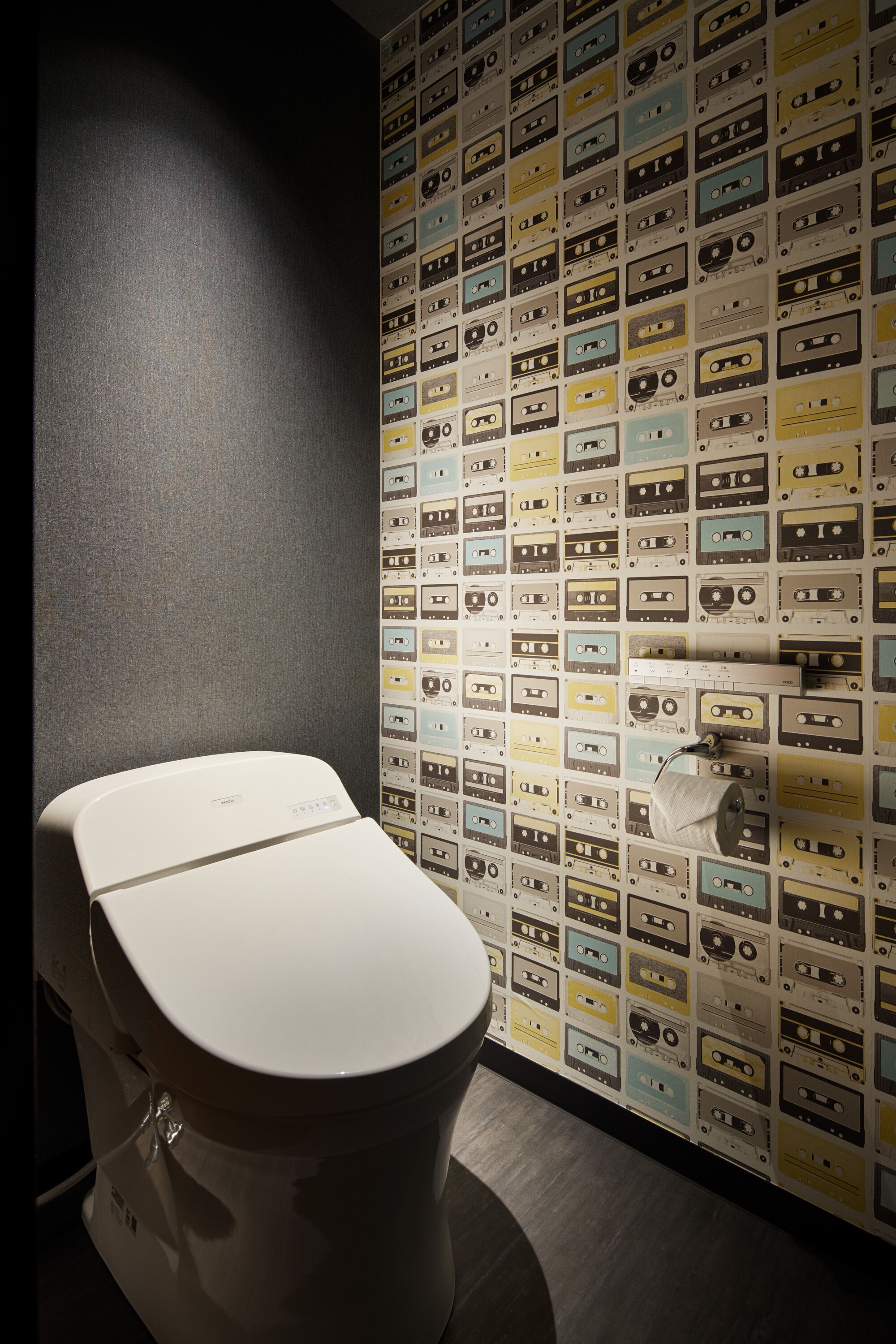 Une salle de bain avec des toilettes et un mur recouvert de cassettes audio.