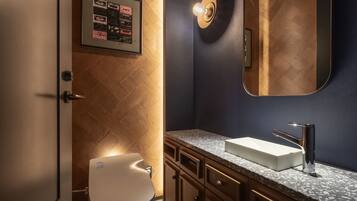 A modern bathroom with a large mirror, a white sink, and wooden cabinetry.