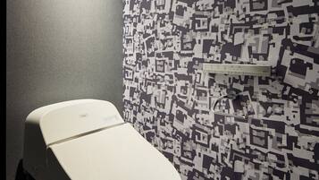 Un inodoro en un baño con pared estampada y una repisa encima.