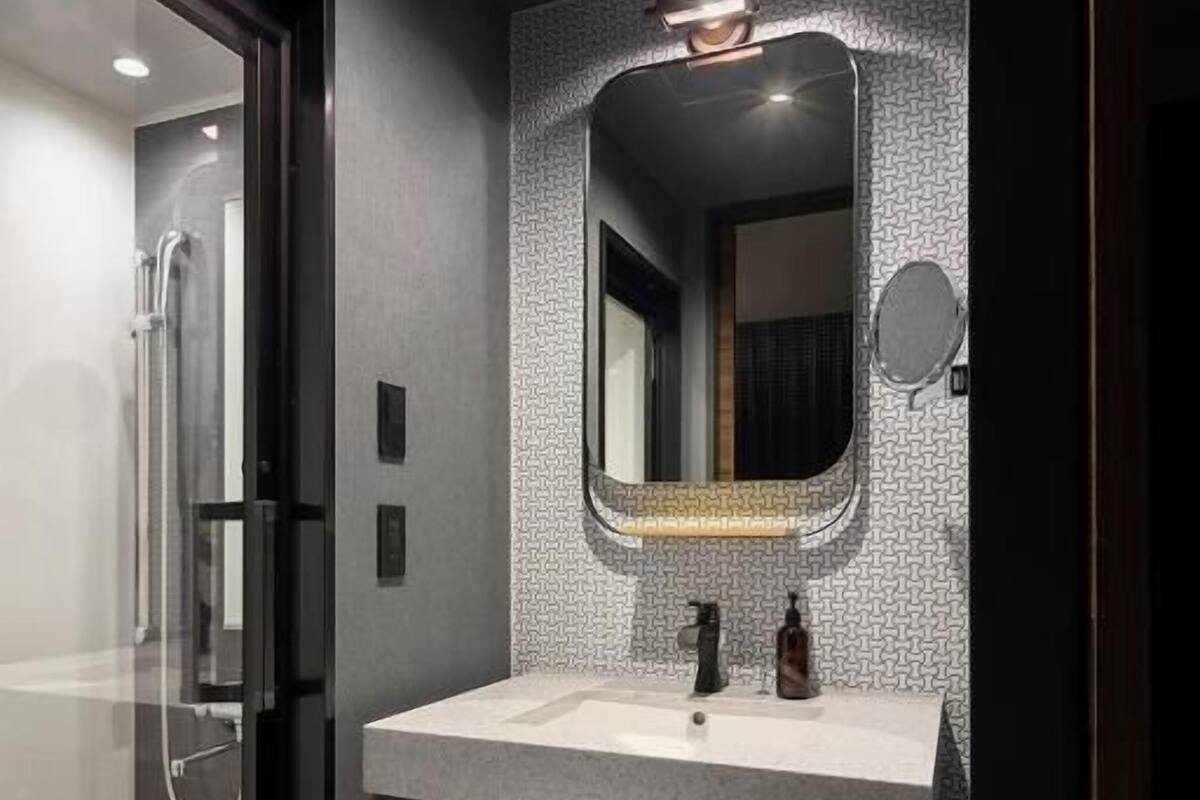 A modern bathroom with a glass shower enclosure, a vanity with a mirror, and a towel rack.