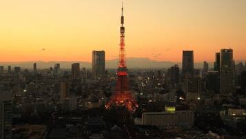 A cityscape with a prominent tower illuminated in red, surrounded by modern buildings and a clear sky.