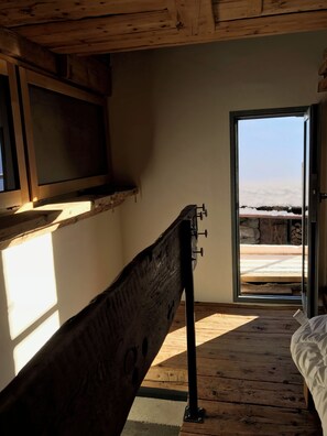 A room with a wooden bench, a bed, and a window with a view of a snowy landscape. - ATTIC VALAISAN TYPICAL (Mase)