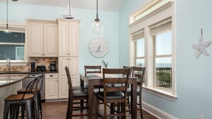 A kitchen with white cabinets, a dining table with chairs, a clock, and a star decoration on the wall.