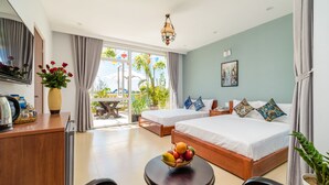 Habitación de hotel con dos camas, zona de comedor y balcón con vista al mar.