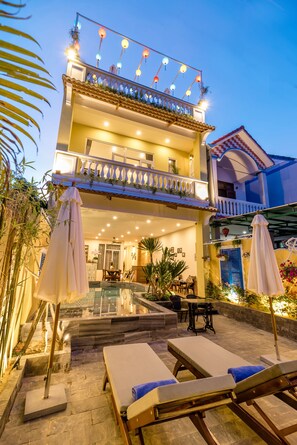 A two-story building with a balcony, outdoor seating area, and a pool. - Golden Walls Homestay (Da Nang)