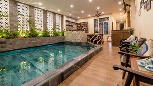 Zona de piscina con borde de azulejos, asientos junto a la piscina y un ventilador de techo.