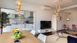 A modern kitchen with a flat-screen TV, dining table with chairs, and a living area with a sofa and coffee table. - Apartment Sunniva by LovelyStay (Funchal)