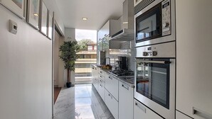 A modern kitchen with stainless steel appliances, a central island, and a large window providing natural light. - Apartment Sunniva by LovelyStay (Funchal)