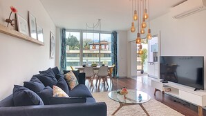 A modern living room with a sofa, TV, and dining area. - Apartment Sunniva by LovelyStay (Funchal)