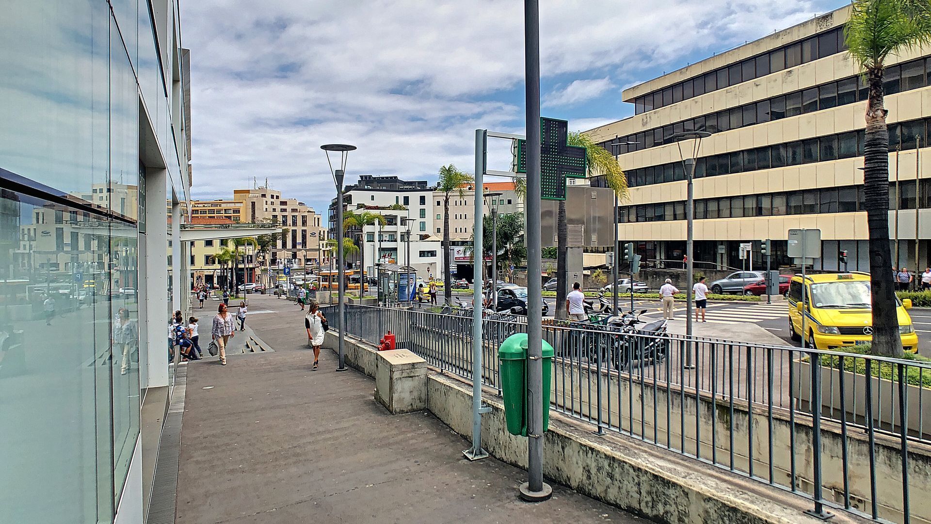 Une rue de la ville avec des immeubles, un trottoir et un taxi jaune.