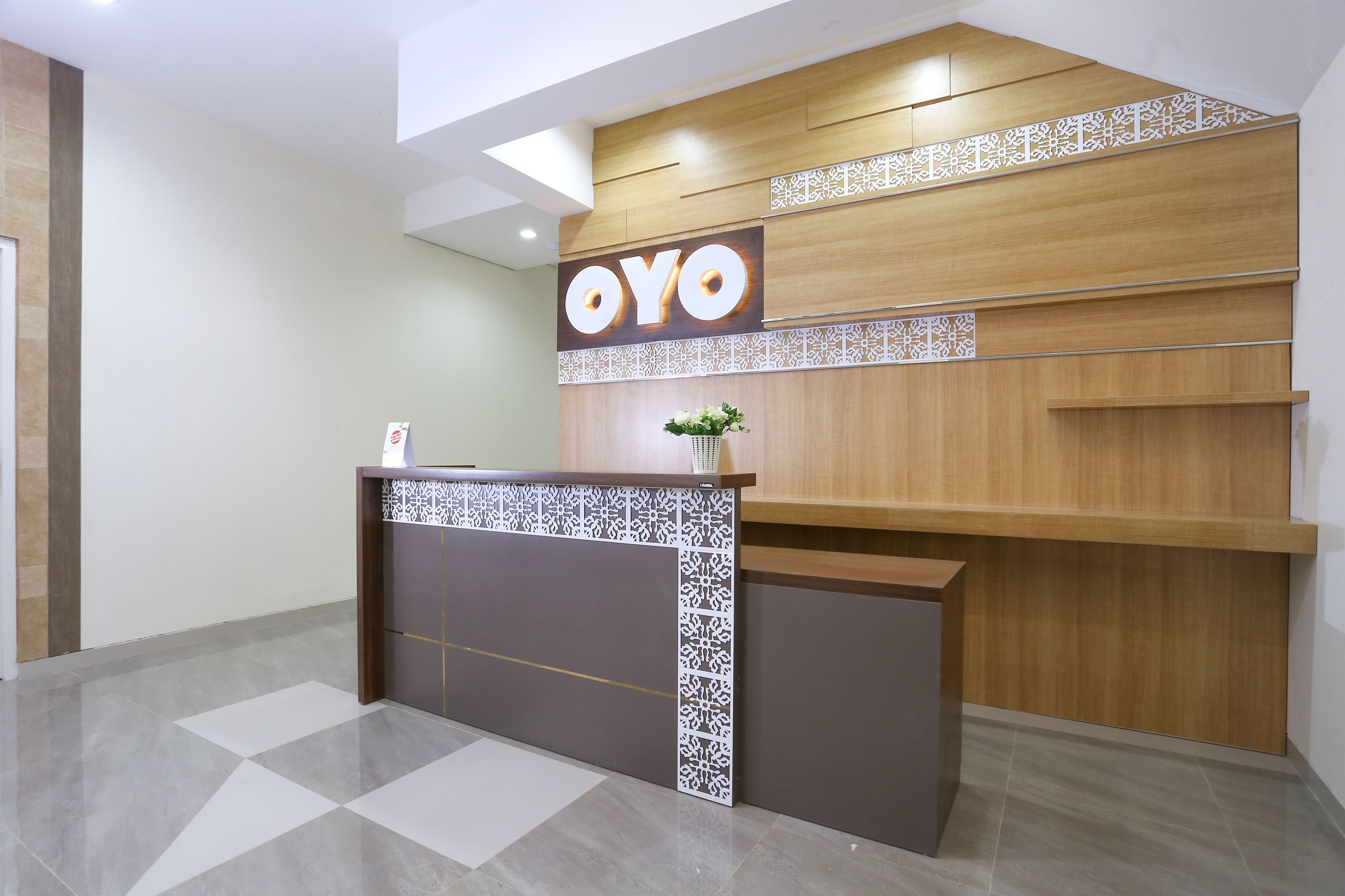 A reception desk with a wooden finish and a sign that reads "OYO".