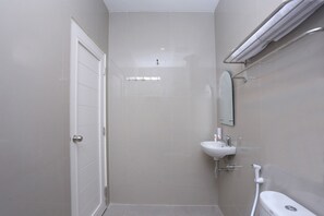 Une salle de bain avec une porte blanche, un lavabo, un miroir et des toilettes.