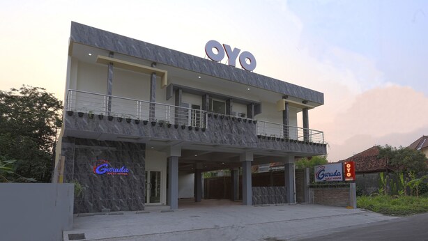 A modern building with a prominent 'OYO' sign, a 'Garuda Guest House' sign, and a covered entrance area. - OYO 999 Garuda Guesthouse (Ngaglik)