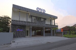 Un edificio moderno con un letrero grande que dice 'OYO', un letrero que indica 'Garuda Guest House' y un área de entrada cubierta.