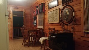 A cozy cabin interior with a wooden interior, a television, a dining table with chairs, and a fireplace.