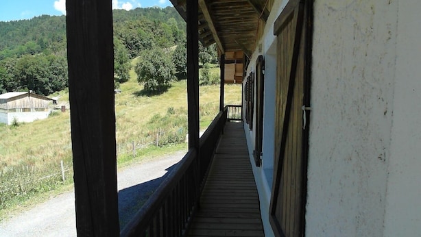 A wooden balcony with a view of a rural landscape, including a house and trees. - Renovated farmhouse with panoramic views  (Le Bouchet Mont Charvin)